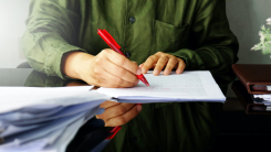 Person annotating paper with red pen