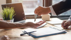 person handing over keys to another person over desk