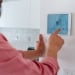 man adjusting smart thermostat